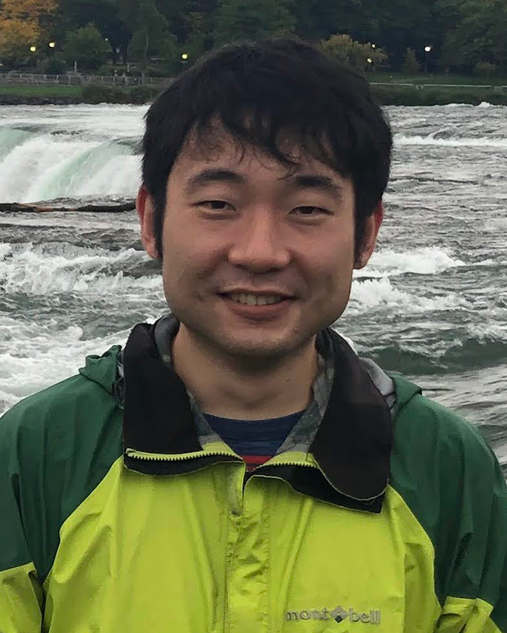 Morie Ishida standing outdoors in front of a waterfall