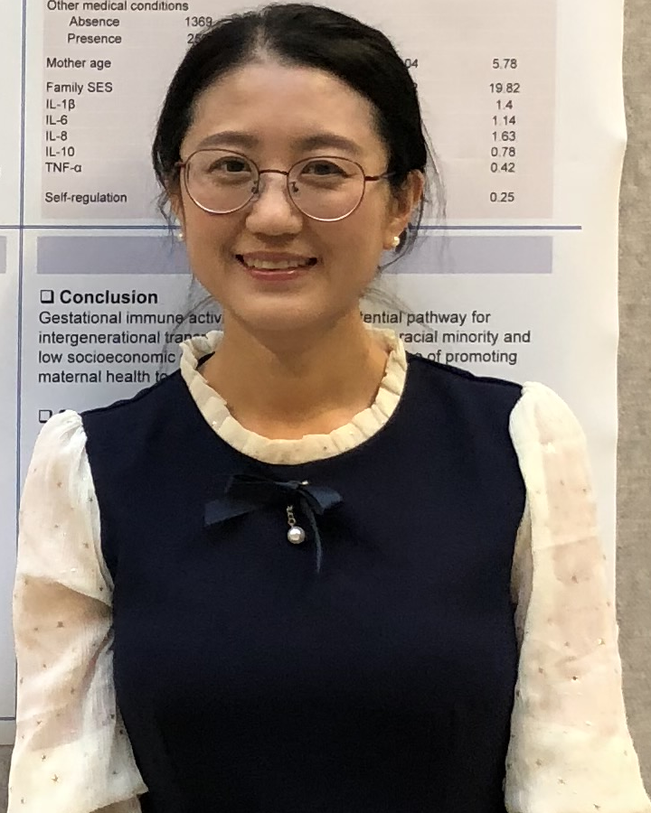 Jing Yu standing in front of her research poster at a conference