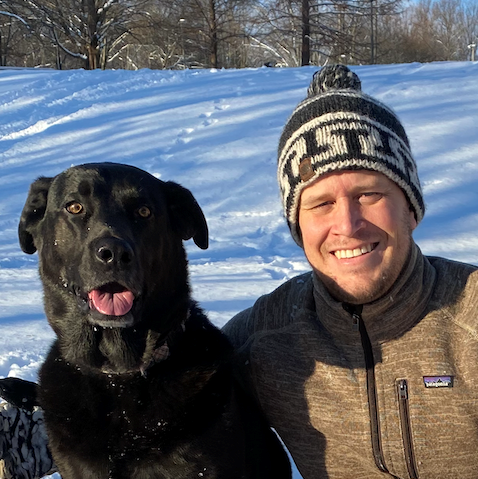 Paul Atkins out in the snow with his black Labrador