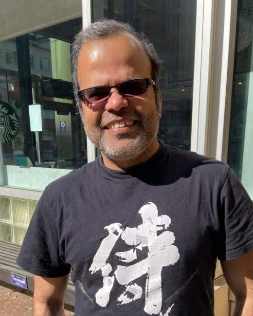 Parmit Singh wearing sunglasses and a black T-shirt with the Japanese character for samurai