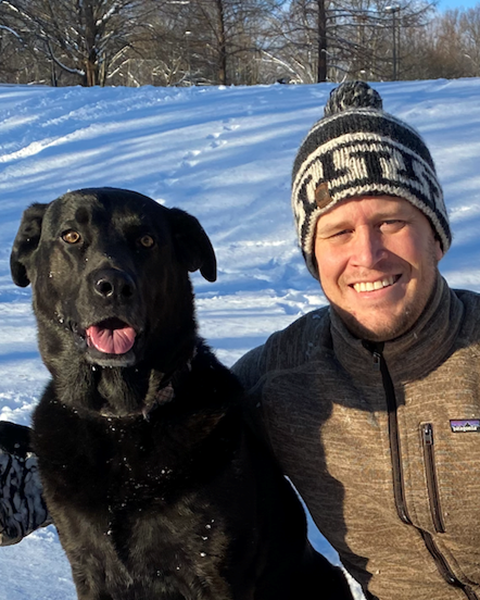 Paul Atkins out in the snow with his black Labrador