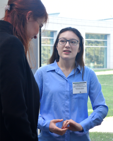 Two fellows chat while standing in front of a bright window