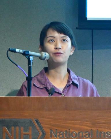 A fellow in a dark red collared shirt stands behind a lectern