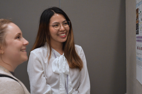 Two fellows grin while reading a research poster