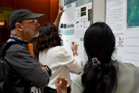 Dr. Ajay Chitnis at a poster session, observing a fellow discuss their poster